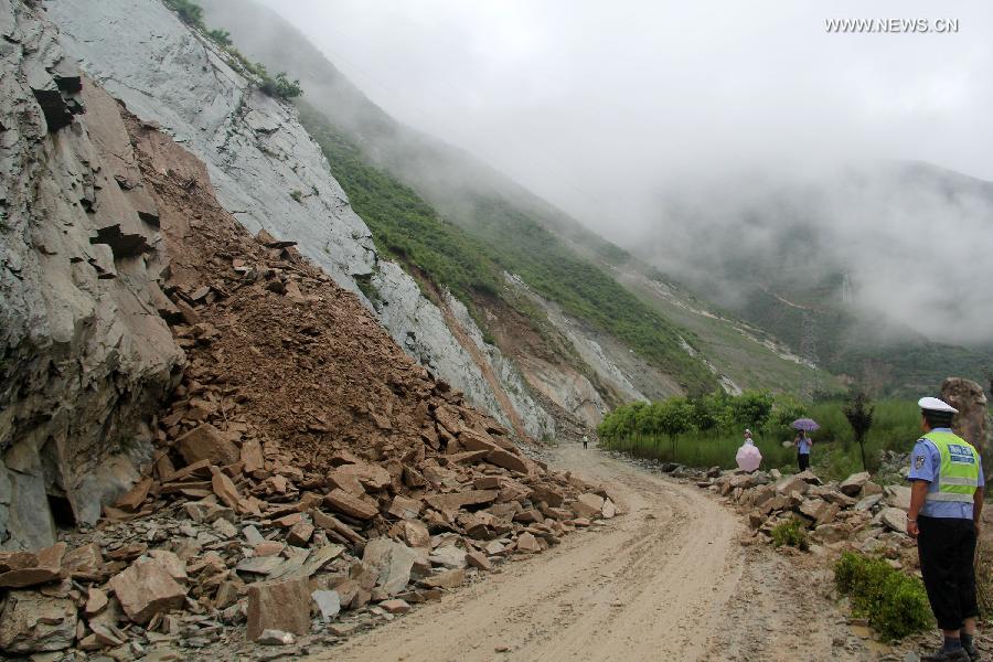 Traffic police are on duty at the landslide-hit highway linking Wenxian County and Bikou Township in northwest China's Gansu Province, July 9, 2013. Rainstorms battered the region these days. (Xinhua)