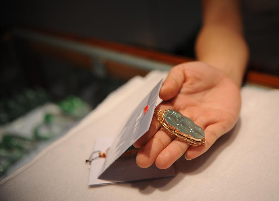 An exhibitor shows a jade pendant at the 2013 China Pan-Asia Stone Expo in Kunming, capital of southwest China's Yunnan Province, July 10, 2013. The eight-day expo kicked off Wednesday at the Kunming International Convention and Exhibition Center. (Xinhua/Qin Lang)