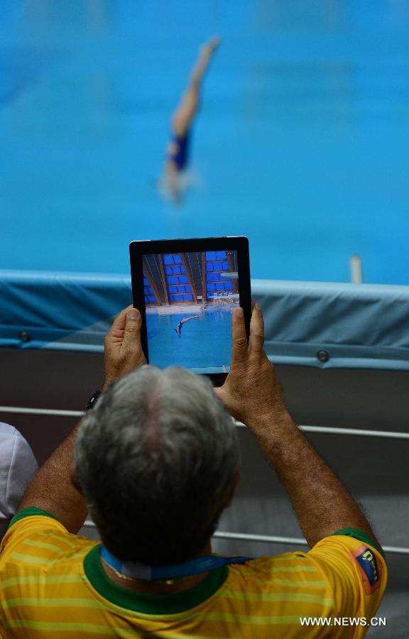 A spectator takes photos of Jia Dongjin during the final women's 3m Spingboard diving at the 27th Summer Universiade in Kazan, Russia, July 10, 2013. Jia Dongjin won the silver medal with 312.75. (Xinhua/Kong Hui)