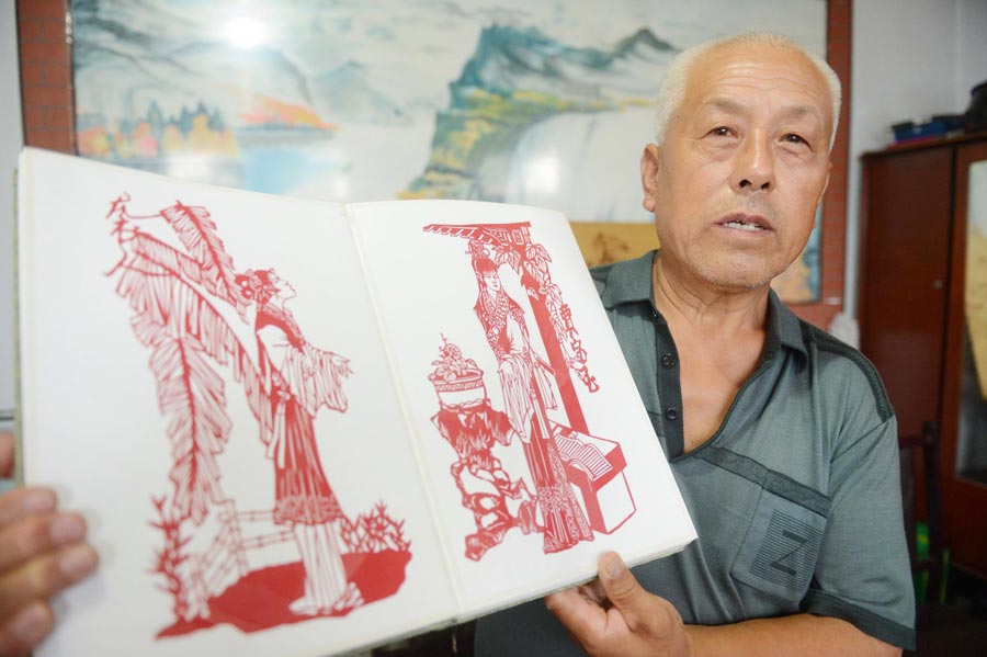 Li Xiangkui, 65, shows his paper-cut designs of characters from the book "Dream of Red Mansions" in Cangzhou, Hebei province, July 7, 2013. (Photo/Xinhua)