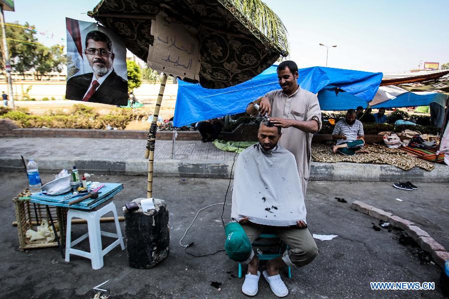 A supporter of Egypt's deposed President Mohamed Morsi has his hair cut near Rabaa Al-Adaweya square in Nasr City, Cairo, Egypt, July 10, 2013. Egypt's armed force has warned in a statement against any attempt to disrupt the country's "difficult and complex" transition. (Xinhua/Amru Salahuddien)