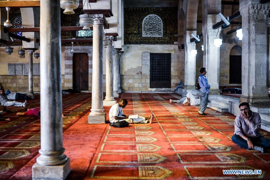 An Egyptian Muslim reads Quran waiting for the time to break their fast at Al-Azhar Mosque on the first day of the holy month of Ramadan in Cairo, Egypt, July 10, 2013. (Xinhua/Qin Haishi) 