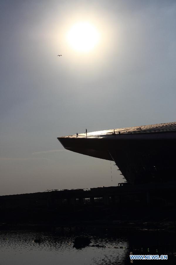 Laborers work atop the Olympic sports center under construction in heat in Shaoxing City, east China's Zhejiang Province, July 10, 2013. (Xinhua/Li Ruichang)