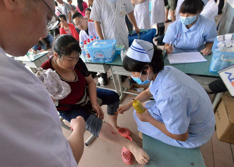 People in flood-hit Zhongxing county get medical treatment in a temporary settlement, southwest China's Sichuan province, July 10, 2013. Rain-triggered mountain torrents and landslides buried 11 households, leaving two people dead and 21 missing. As of 9:45 p.m., 352 people stranded have been relocated to safe areas. (Xinhua/Liu Jie) 