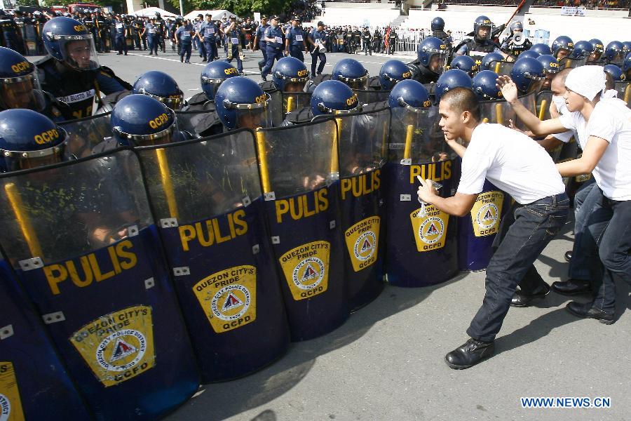 Mock protestors clash with members of the Civil Disturbance Management (CDM) of the Philippine National Police (PNP) during the CDM Competition in Manila, the Philippines, July 11, 2013. The competition aimed to assess the effectiveness and efficiency of the CDM Units on the police operational procedures in handling civil disturbance. (Xinhua/Rouelle Umali)