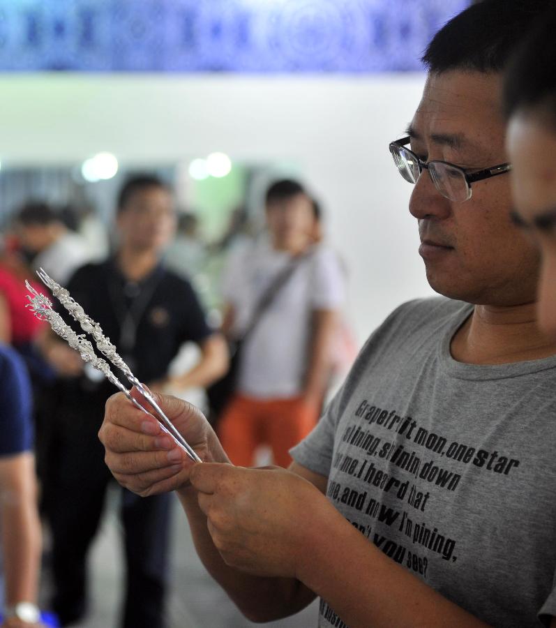 A visitor looks at a silverware during a folk handicraft exhibition in Beijing, capital of China, July 11, 2013. The five-day exhibition, opened on Thursday, displayed folk handicrafts made in southwest China's Guizhou Province. (Xinhua/Li Wen) 