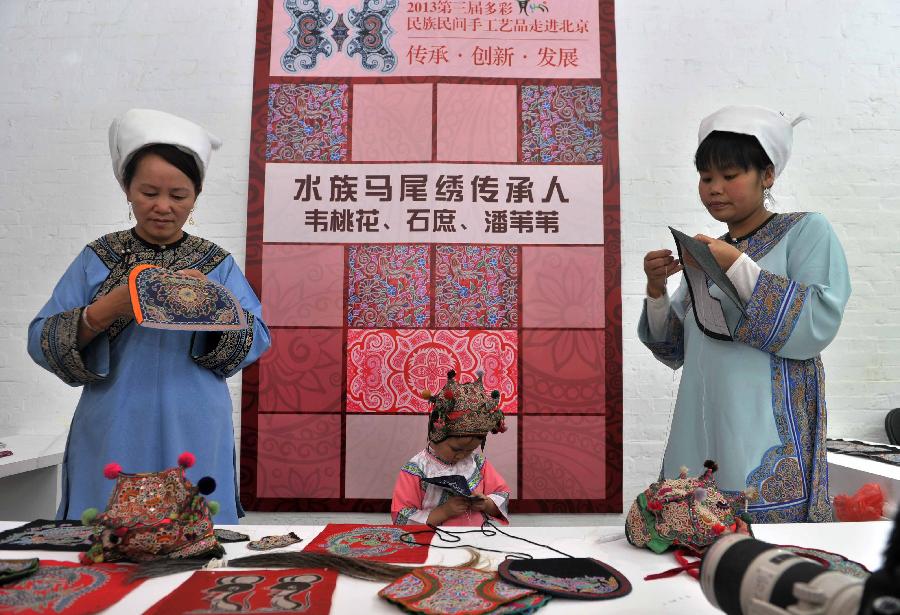 Three generations show horsetail embroidery skills of the Shui ethic group during a folk handicraft exhibition in Beijing, capital of China, July 11, 2013. The five-day exhibition, opened on Thursday, displayed folk handicrafts made in southwest China's Guizhou Province. (Xinhua/Li Wen)