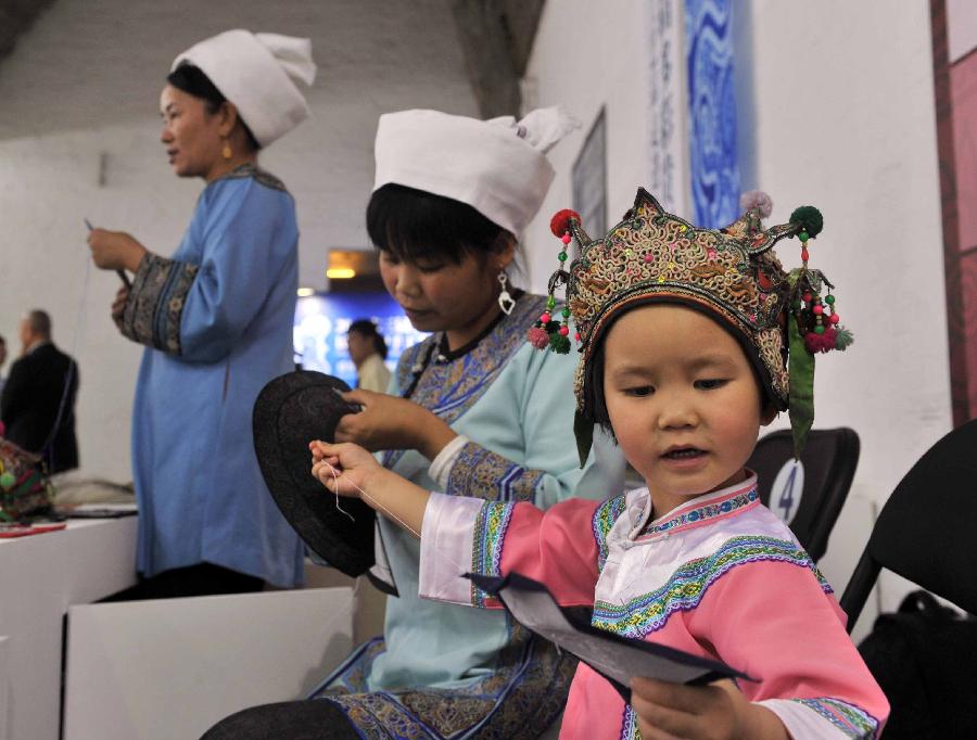 Three generations show horsetail embroidery skills of the Shui ethic group during a folk handicraft exhibition in Beijing, capital of China, July 11, 2013. The five-day exhibition, opened on Thursday, displayed folk handicrafts made in southwest China's Guizhou Province. (Xinhua/Li Wen) 