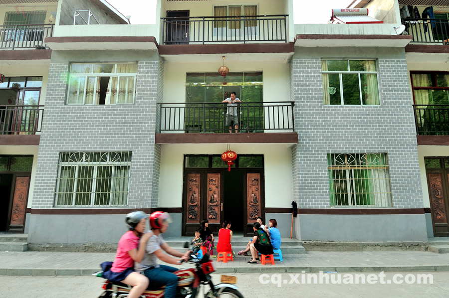 People chat in front of their newly built houses in the eco-migration community. The eco-migration project aims to help the poor overcome extreme difficulties in Chengkou county, Chongqing, southwest China. (Xinhua Photo/ Li Xiangbo)