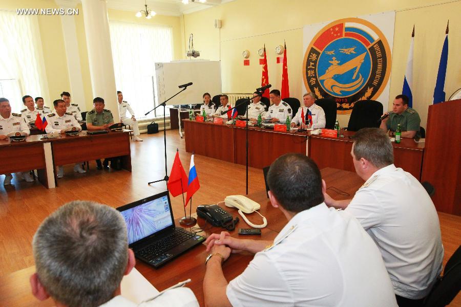 Naval officers from China and Russia discuss and summarize the drills at the closing ceremony of the joint naval drills in Vladivostok, Russia, July 11, 2013. Ding Yiping, deputy commander of the Chinese Navy and director of the "Joint Sea-2013" drill, announced the end of the joint naval drills here on Thursday. (Xinhua/Zha Chunming)