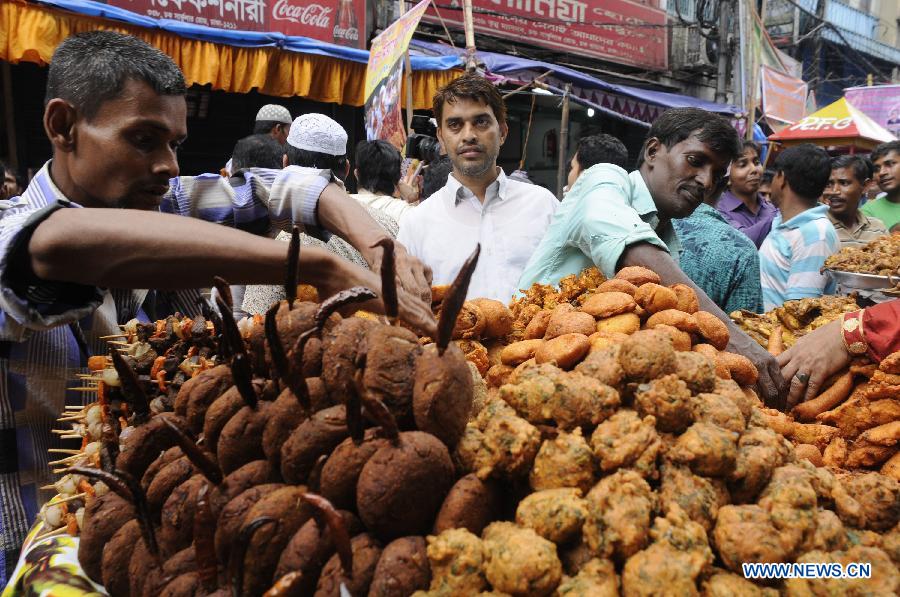 Bangladeshi Muslims buy ifter, food for breaking the daytime fast during the Islamic holy month of Ramadan, at a traditional ifter bazaar in Dhaka, Bangladesh, July 11, 2013. Ramadan is the Muslim month of fasting, during which Muslims refrain from eating, drinking, smoking from sunrise to sunset. (Xinhua/Shariful Islam)