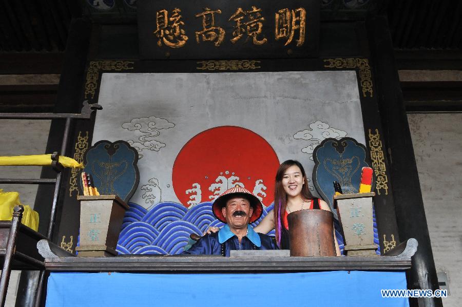 Zhang Shucheng (L), a 65-year-old retiree acting "Xian Tai Ye", the title of county chief in ancient China, poses for a photo with a tourist in Pingyao County, north China's Shanxi Province, July 11, 2013. No matter whether they are natives, migrators or tourists, they have their own stories in this ancient town. (Xinghua/He Canling)