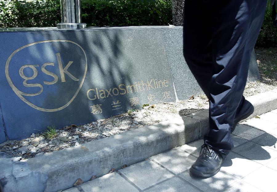 A pedestrian walks past a sign of GlaxoSmithKline (GSK), Britain's biggest drug maker, in Shanghai, east China, July 12, 2013. Some senior executives from GlaxoSmithKline(China) Investment Co., Ltd are being investigated for suspected bribery and tax-related violations, Chinese police said Thursday. (Xinhua/Ding Ting) 