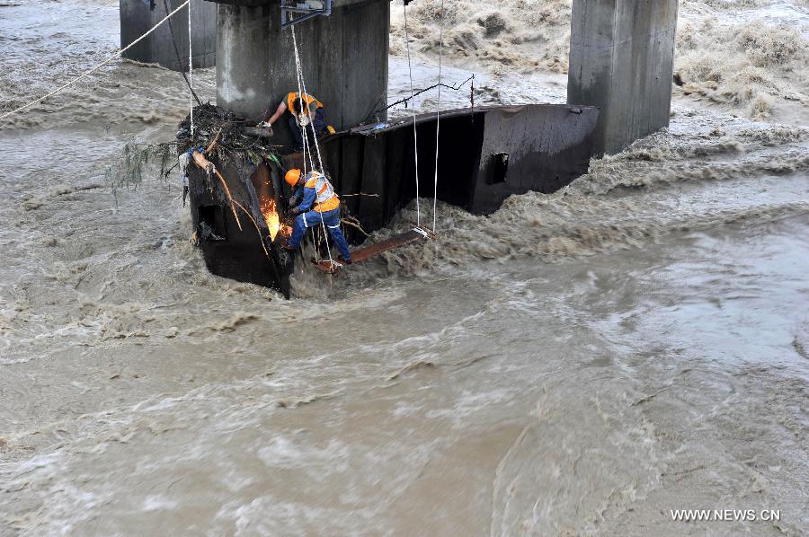 Rescue workers cut apart the iron barge stuck at a pier of the Qingbaijiang Bridge of the Baocheng Railway in Chengdu, capital of southwest China's Sichuan Province, July 12, 2013. Affected by the rain-triggered floods, an iron barge hit the Qingbaijiang Bridge on July 9, causing damages to some sections of the bridge. (Xinhua/Wang Zhengwei) 