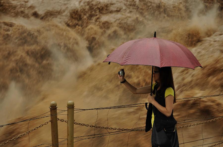 A tourist takes photos of the Hukou Waterfall of the Yellow River from the site in Jixian County, north China's Shanxi Province, July 12, 2013. Triggered by non-stop heavy rainfall in the upper reaches, the rising water level of the Yellow River surged the Hukou Waterfall, attracting many visitors. (Xinhua/Lu Guiming) 