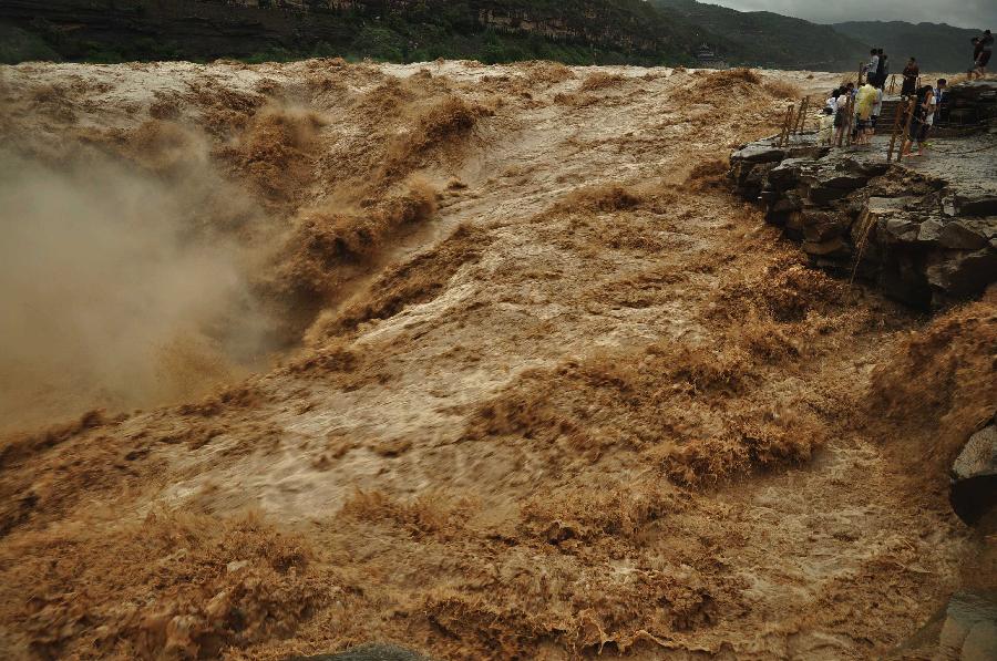 Tourists take photos of the Hukou Waterfall of the Yellow River from the site in Jixian County, north China's Shanxi Province, July 12, 2013. Triggered by non-stop heavy rainfall in the upper reaches, the rising water level of the Yellow River surged the Hukou Waterfall, attracting many visitors. (Xinhua/Lu Guiming)