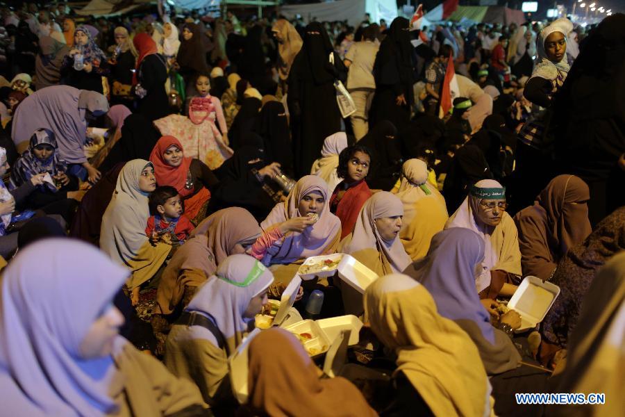 A woman carrying food walks among female protesters during a pro-Morsi protest near the Rabaa al-Adawiya mosque, in Cairo, Egypt, July 12, 2013. (Xinhua/Wissam Nassar) 