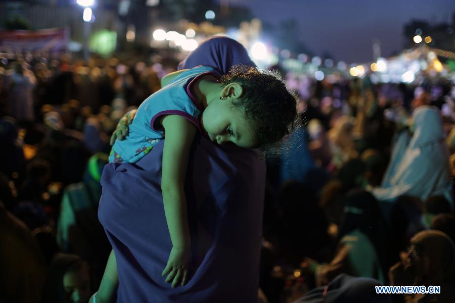 A woman carries her child among female protesters during a pro-Morsi protest near the Rabaa al-Adawiya mosque, in Cairo, Egypt, July 12, 2013. (Xinhua/Wissam Nassar) 