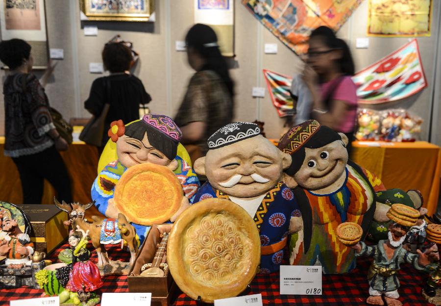 Visitors view the displayed items in an exhibition held in Urumqi, capital of northwest China's Xinjiang Uygur Autonomous Region, July 12, 2013. The first session of Xinjiang Presents Design Competition that kicked off from April has received more than 900 pieces of artworks including sculptures, paintings, embroidery, paper cutting and pottery. (Xinhua/Wang Fei) 