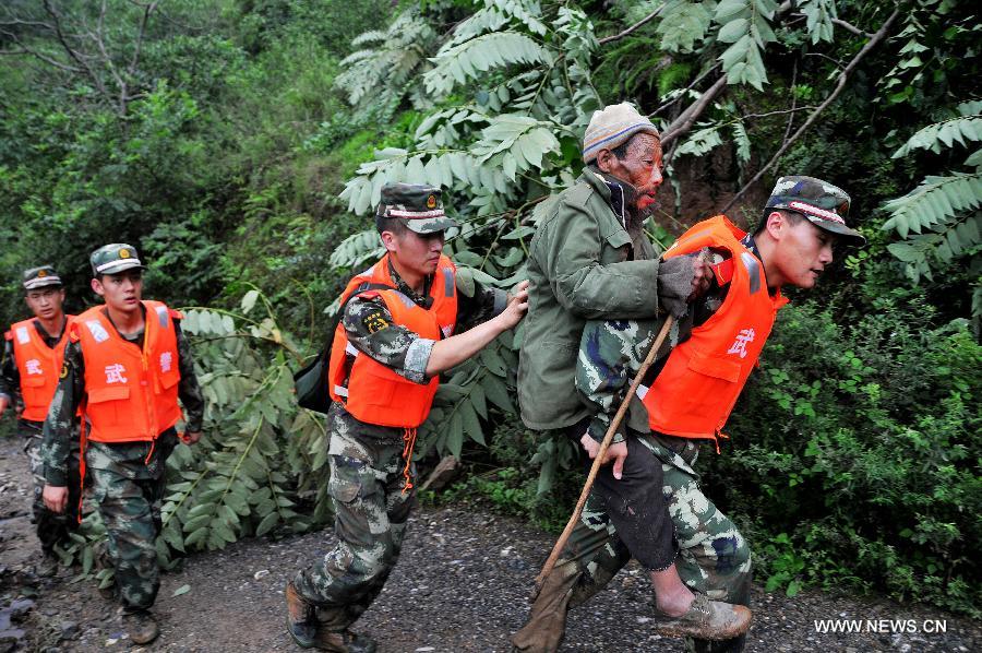 Rescuers help transfer an old man to a safety place in Hongxi Village of Pingwu County in Mianyang City, southwest China's Sichuan Province, July 12, 2013. Four people were injured and one was missing in a rain-triggered mudslide on Friday. Most of the houses in the village were buried in the mud. (Xinhua/Hu Yu)  