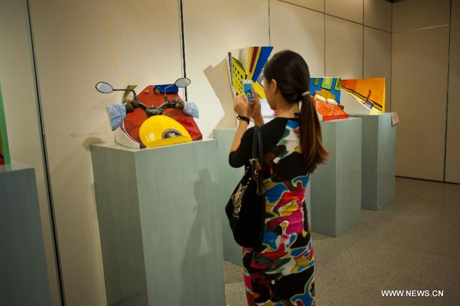 A visitor views a sculpture displayed at an exhibition of excellent sculpture works of 2013 college graduates in Beijing, capital of China, July 13, 2013. Over 100 works submitted by art academies nationwide are presented to the public from Saturday on here. (Xinhua/Zhang Cheng)