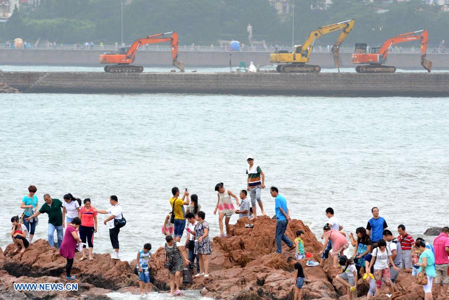 Tourists play on the reef near the Zhanqiao Bridge in Qingdao, east China's Shandong Province, July 14, 2013. A renovation work has been started to repair the Zhanqiao Bridge, a landmark for Qingdao. Part of the bridge was hit and destroyed by thunderstorms and waves on May 27. (Xinhua/Li Ziheng)  