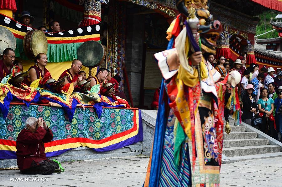 Visitors watch buddhists wearing masks attending a ceremony expressing stories of Gods and ghosts in Tibetan Buddhism at the Taer Monastery in Huangzhong County of Xining, capital of northwest China's Qinghai Province, July 14, 2013. The ceremony, which is called "Tiao Qian" in Chinese, was held on Sunday here at the monastery, the birth place of Tsongkhapa, founder of the Geluk school of Tibetan Buddhism. (Xinhua/Wu Gang)