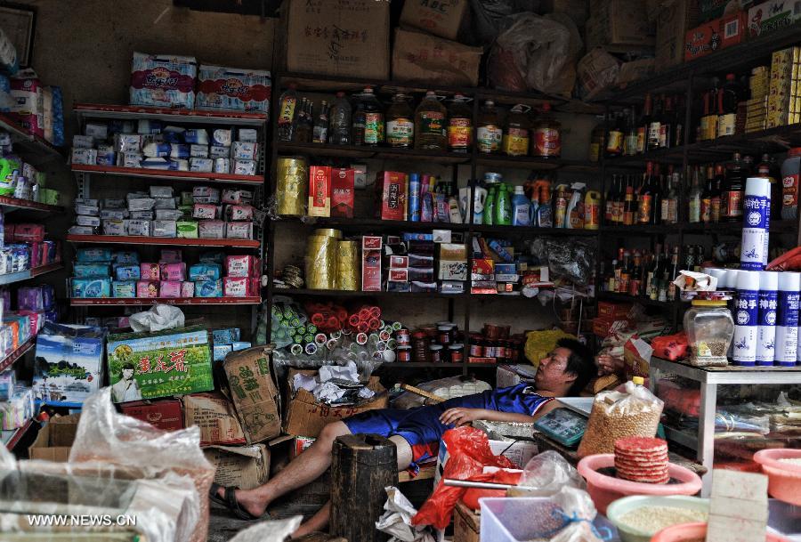 A shop owner takes a nap in his shop in the Miao Autonomous County of Chengbu, central China's Hunan Province, July 13, 2013. An ecology tourism festival is held here from July 12 to 14. (Xinhua/Cheng Tingting)