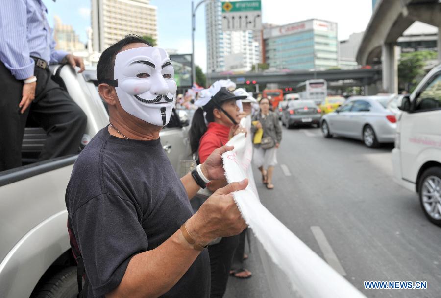 A protester wearing a mask holds a banner during a rally in central Bangkok, capital of Thailand, July 14, 2013. A number of anti-government protesters rallied in Bangkok and other ten more provinces in Thailand. (Xinhua/Gao Jianjun)