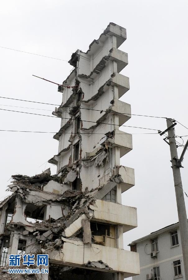 A piece of wall stands precariously after a demolition in Wuhan, Hubei province, July 14, 2013. The 10-storey building was under demolition and the middle part removed, leaving concrete slabs on both sides. The piece of wall, without any safety measures, is next to a 5-storey residence, triggering fear from nearby residents and passing pedestrians. (Photo/Xinhua)
