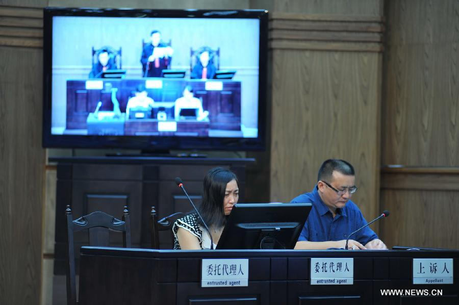 Tang Hui (L), mother of a young rape victim who sued a local authority for putting her into a labor camp, attends the court hearing in The Hunan Provincial People's High Court in Changsha, capital of central China's Hunan Province, July 15, 2013. The Hunan Provincial People's High Court on Monday ordered the Yongzhou municipal re-education through labor commission to pay Tang Hui 2,941 yuan (478 U.S. dollars) in compensation for infringing upon her personal freedom and causing mental damages. The 40-year-old mother appealed to the high court in April after the Yongzhou Intermediate People's Court denied her request for an apology and compensation from the re-education through labor commission. Tang was put into the labor camp after she publicly petitioned for harsher punishments for those found guilty of raping her daughter and forcing her into prostitution. (Xinhua/Long Hongtao) 