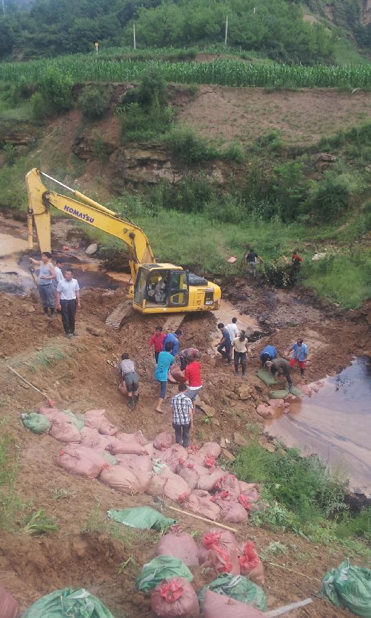 Workers set up a defence dam in the lake in Zichang County, northwest China's Shaanxi Province, July 15, 2013. The oil pipe from Ansai County to Yongping Town was damaged by mudslide following days of rainstorms. Rescue efforts for repairing the broken pipe are underway. (Xinhua)