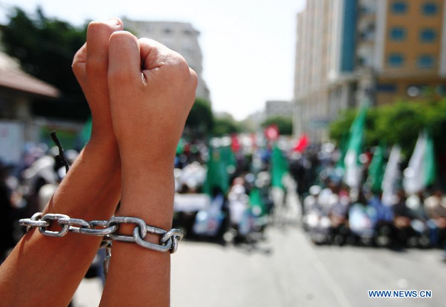 A Palestinian protestor takes part in a protest to demand release of Palestinian prisoners held by Israel outside Red Cross office in Gaza City, on July 15, 2013. (Xinhua/Stringer)