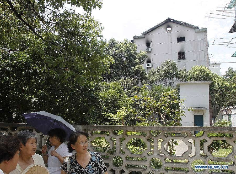 Locals look on outside a residential building at Yangpu District in Shanghai, east China, July 16, 2013. A fire broke out at the five-storey building early Tuesday, leaving two people killed. Local fire department took one hour to douse the fire. (Xinhua/Ding Ting) 