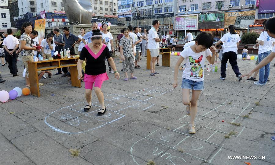 Photo taken on July 15, 2013 shows residents playing game at Hongmen Square in Dongyang City, east China's Zhejiang Province. Many residents participated in the activity of old games organized by students from Zhejiang Normal University on Monday. (Xinhua/Bao Kangxuan) 