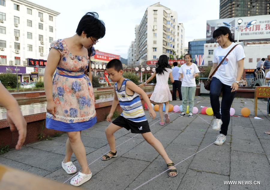 Photo taken on July 15, 2013 shows residents playing game at Hongmen Square in Dongyang City, east China's Zhejiang Province. Many residents participated in the activity of old games organized by students from Zhejiang Normal University on Monday. (Xinhua/Bao Kangxuan) 