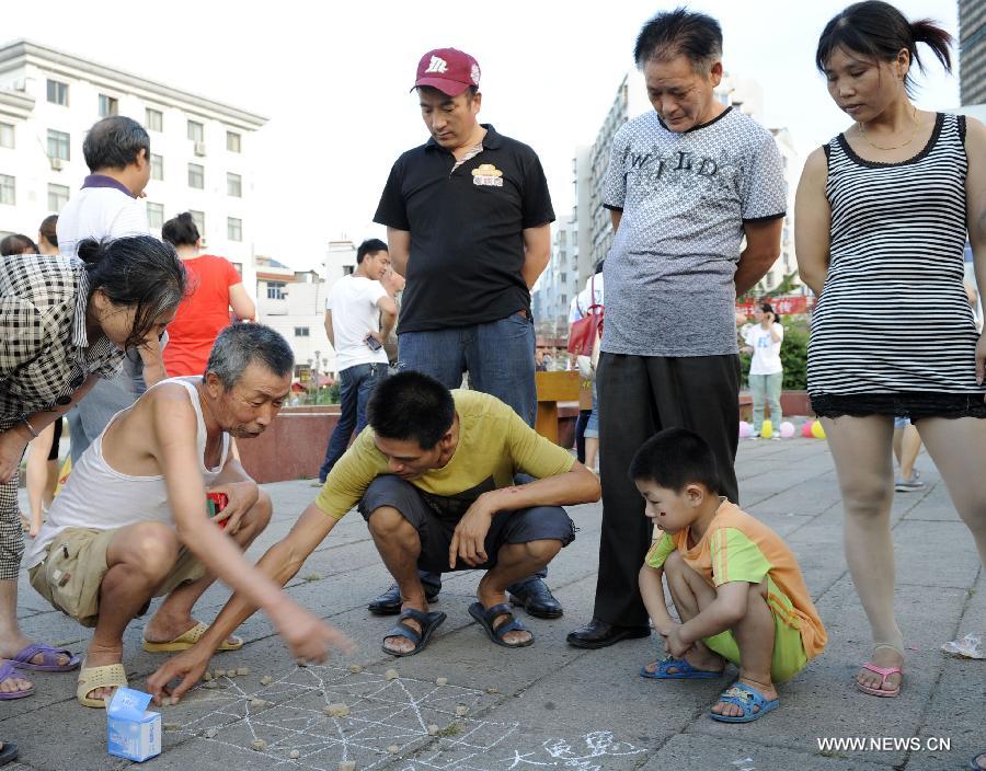 Photo taken on July 15, 2013 shows residents playing "chess" at Hongmen Square in Dongyang City, east China's Zhejiang Province. Many residents participated in the activity of old games organized by students from Zhejiang Normal University on Monday. (Xinhua/Bao Kangxuan)