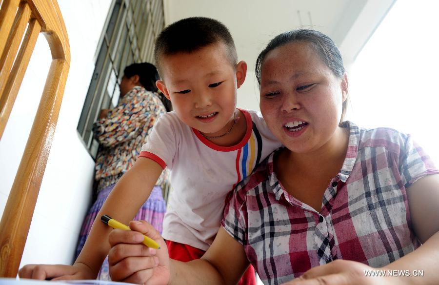 A migrant worker fills the registration form for her child at the Zhaoxia Primary School in Hefei City, east China's Anhui Province, July 16, 2013. A total of 195 sentinel primary schools are opened to the eligible migrant workers' children in the city. (Xinhua/Liu Junxi)