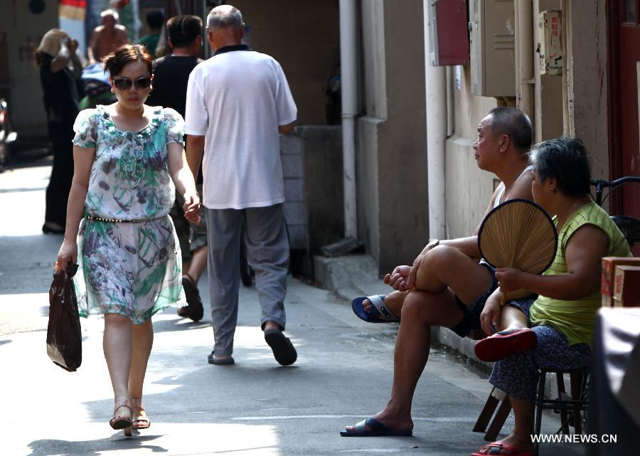 An old couple enjoy cool in the shade in the Baodai residential area of Yuyuan Street, east China's Shanghai, July 16, 2013. Shanghai suffers from high temperature in recent days. (Xinhua/Pei Xin)   