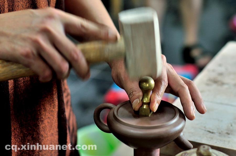 A craftsman stamps "Zhongguo Antao" (literally Chinese Anchang Pottery) seal on a half-made teapot in a workshop in Anfu Town, Rongchang County, Chongqing, July 13, 2013. (Xinhua/Li Xiangbo)