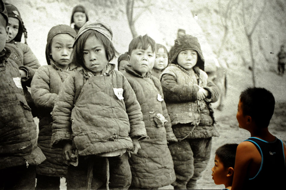 Two pupils view the piece of photographic works "Children in famine" in Henan Museum on July 12, 2013. 127 documentary images were presented in the one-month-long exhibition under the title of "China Central Plains in 1942 under the lens of Forman" in Henan Museum. (Photo/ Xinhua)