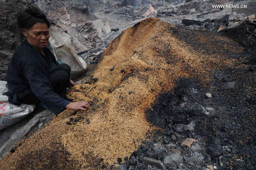 A woman clears the millet up at the accident site in Wusuo Village of Miao ethnic group of Taijiang County, southwest China's Guizhou Province, July 16, 2013. A fire caused the burnout of more than 200 houses on Monday afternoon with no casualties report. (Xinhua)  
