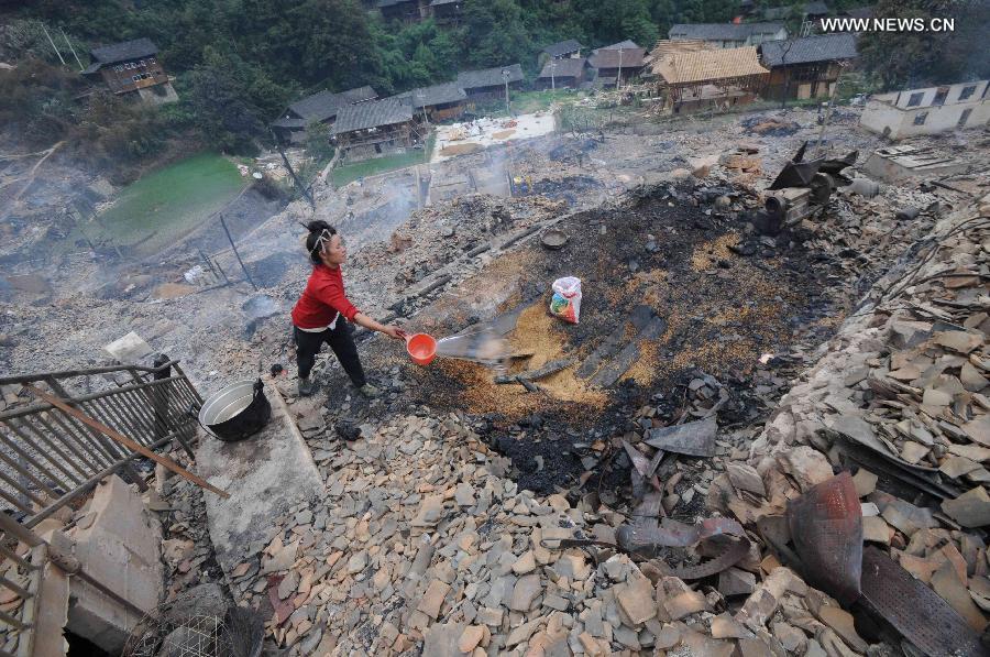 A woman douses the fire at the accident site in Wusuo Village of Miao ethnic group of Taijiang County, southwest China's Guizhou Province, July 16, 2013. A fire caused the burnout of more than 200 houses on Monday afternoon with no casualties report. (Xinhua)  