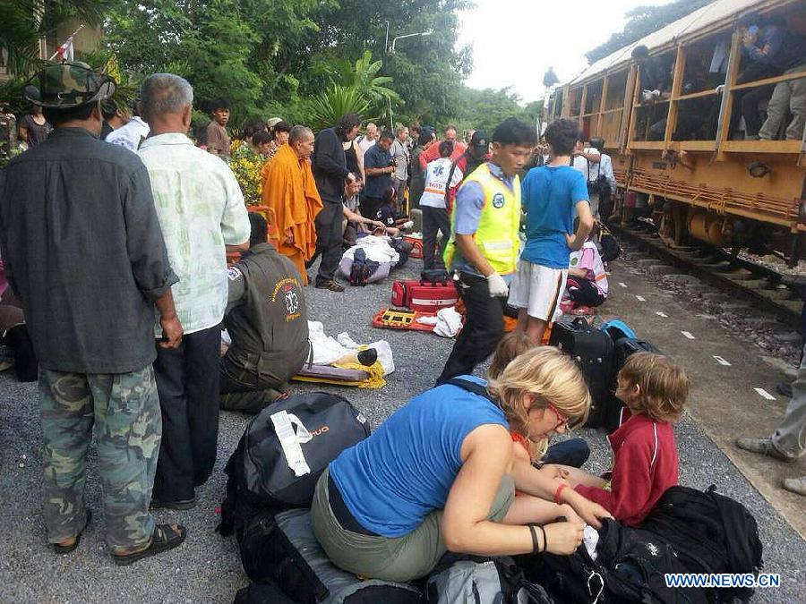 Passengers and rescuers gather at the site where a train derailed near Den Chai district of northern Phrae province, Thailand, on July 17, 2013. 30 people were injured when a train from the capital to northern Thailand derailed on Wednesday early morning. (Xinhua)