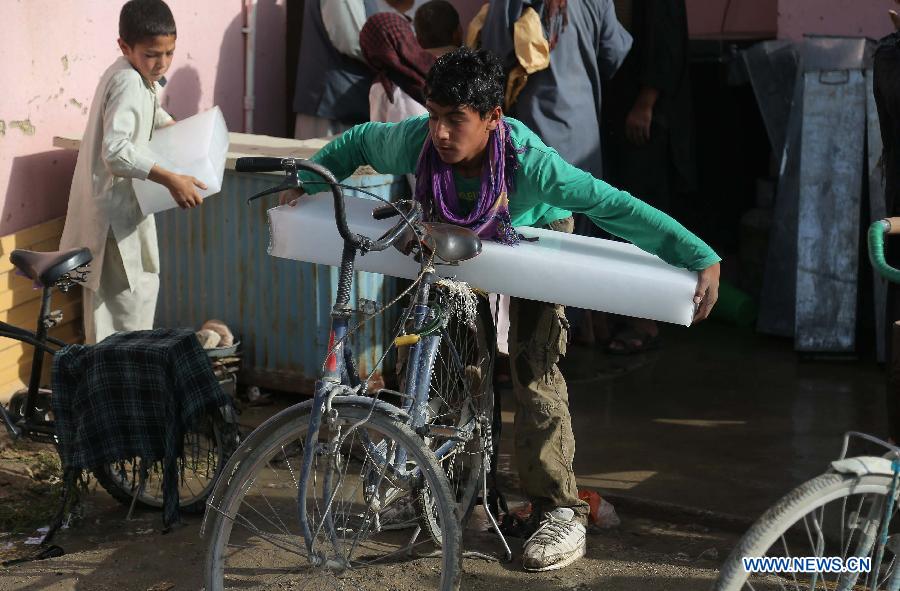 An Afghan boy puts an ice brick on his bicycle at an ice factory in Ghazni province in eastern Afghanistan on July 17, 2013. (Xinhua/Rahmat)