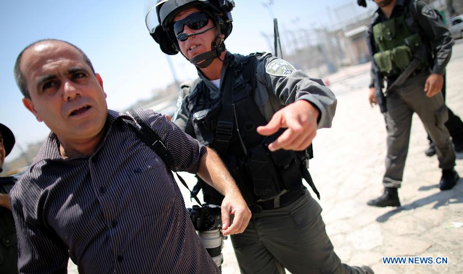 A Palestinian journalist clashes with Israeli soldiers, while Israeli soldiers attacked dozens of Palestinian journalists as they attempted to cross to Jerusalem from Qalandiya checkpoint on July 17, 2013. Palestinian journalists launched a campaign of their freedom of Movement as they are banned from covering with Special Movement Permission from Israel. (Xinhua/Fadi Arouri)