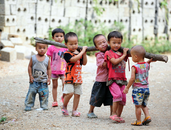 Children carry a log in the Dahua Yao ethnic county of Guangxi Zhuang autonomous region on July 14, 2013. (Photo/Xinhua)