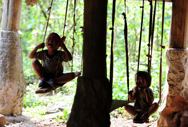 Children play on a swing in the Dahua Yao ethnic county of Guangxi Zhuang autonomous region on July 14, 2013. (Photo/Xinhua)