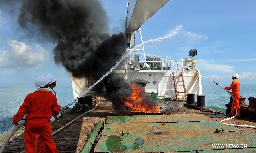 Seamen participate in a maritime fire drill held by the South China Sea Navigation Support Center at the Qiongzhou Strait near Haikou, capital of south China's Hainan Province, July 18, 2013. (Xinhua/Guo Cheng) 