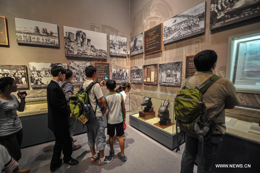 Visitors view the bronze heads of a rat and a rabbit, donated by the Pinault family of France in April, at the National Museum of China in Beijing, capital of China, July 18, 2013. The two pieces of relics were among 12 animal head sculptures that formed a zodiac water clock previously stood at Yuanmingyuan, or the Old Summer Palace, in northwest Beijing. They were looted by Anglo-French Allied forces during the Second Opium War in 1860. (Xinhua/Zhao Dingzhe)